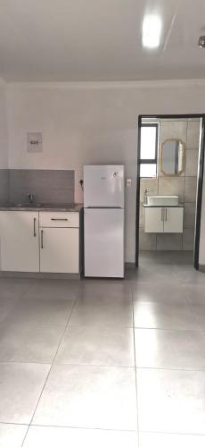 an empty kitchen with a refrigerator and a sink at Entire Self-Catering Apartment in Silverfields in Krugersdorp