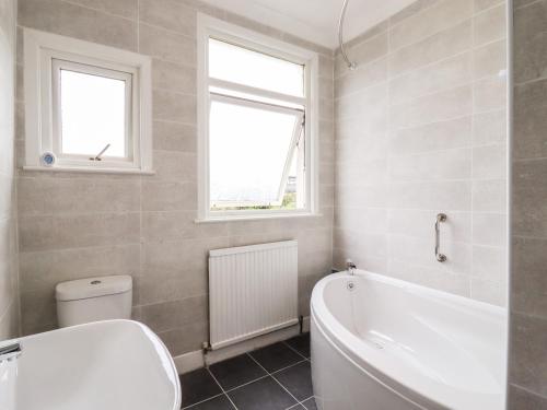 a bathroom with a tub and a toilet and a window at Ninety Eight in Southend-on-Sea