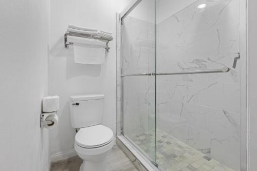 a bathroom with a toilet and a glass shower at Inland Inn & Suites in San Bernardino