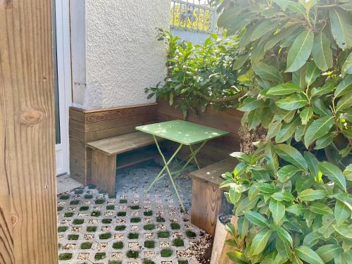 un banc vert assis à côté d'une porte avec des plantes dans l'établissement Studio au cœur du village, à Rillieux-la-Pape