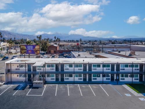 a building in a parking lot with mountains in the background at Inland Inn & Suites in San Bernardino