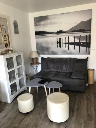 - un salon avec un canapé en cuir noir et deux tabourets dans l'établissement Les pieds dans l'eau, à Saint-Malo