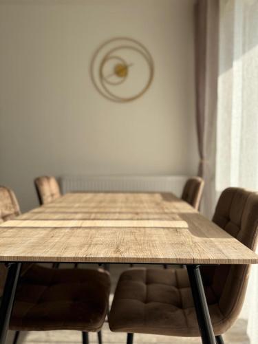 a dining room table with chairs and a clock on the wall at Le Colisée à deux pas in Mainvilliers
