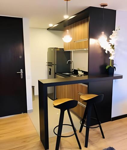 a kitchen with a black counter and two stools at Domus Suites Chia in Chía