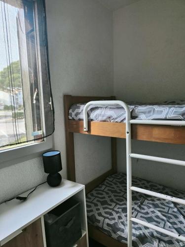 une petite chambre avec deux lits superposés et une fenêtre dans l'établissement Résidence Caraibes - Appartement 3 pièces climatisé, avec accès WIFI à LE BARCARES - CAP COUDALERE MAE-8051, au Barcarès
