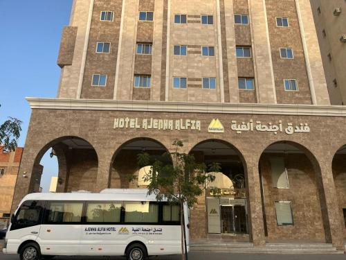 a white bus parked in front of a building at فندق أجنحة ألفية Hotel AJENHA ALFIA in Al Madinah