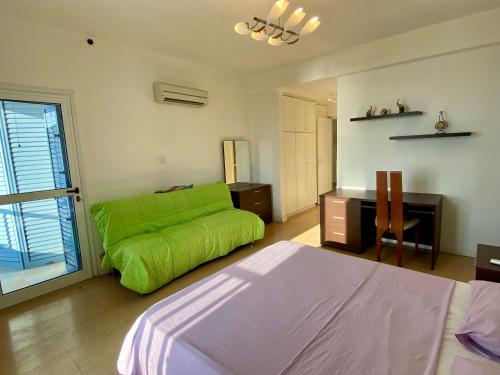 a living room with a green couch and a desk at Sea Front Villa Ekaterina in Paphos City