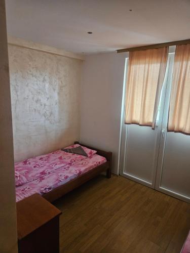 a small bedroom with a pink bed and two windows at Guest House Ethno Village Milogora in Pluzine