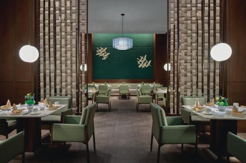 a restaurant with tables and chairs and a green wall at Holiday Inn Wuhan Tianhe Airport by IHG in Wuhan