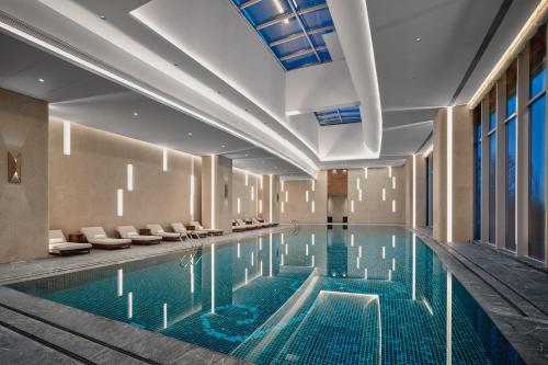 a swimming pool in a hotel with chairs and tables at Holiday Inn Wuhan Tianhe Airport by IHG in Wuhan