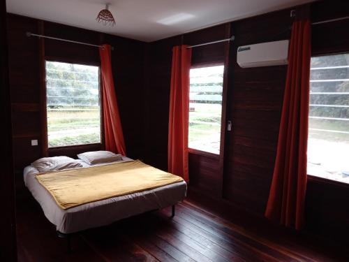 a small bed in a room with two windows at Palavas la crique in Saint-Laurent du Maroni