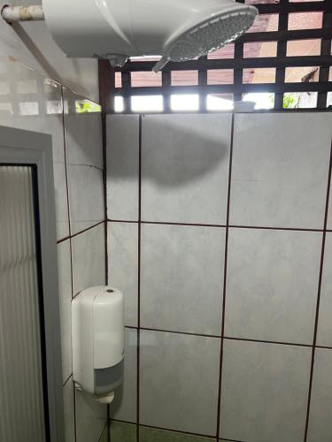 a bathroom with a white tiled wall with a urinal at Cabinas Lupita in Fortuna