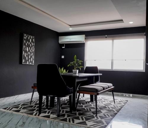 a dining room with a table and chairs on a rug at Spacious Black Themed Apartment Victoria Island in Lagos