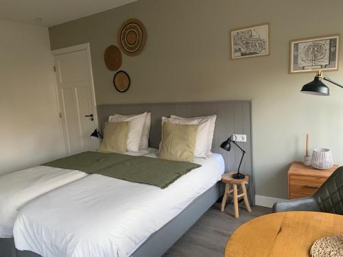a bedroom with a bed with a table and a chair at De Logeerkamer Gapinge in Gapinge