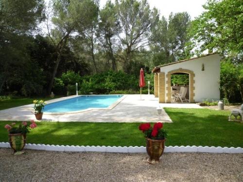 une cour avec une piscine et deux vases fleuris dans l'établissement Charming villa Pont-du-Gard - 6 to 8 people, à Vers-Pont-du-Gard