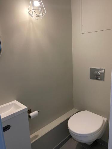 La salle de bains est pourvue de toilettes blanches et d'une lampe. dans l'établissement L'APPART, proche mer et centre-ville, rénové en 2021, à Neufchâtel-Hardelot