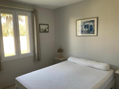 a bedroom with a white bed and a window at Maison bercée par le bruit de la mer île de ré in Sainte-Marie-de-Ré