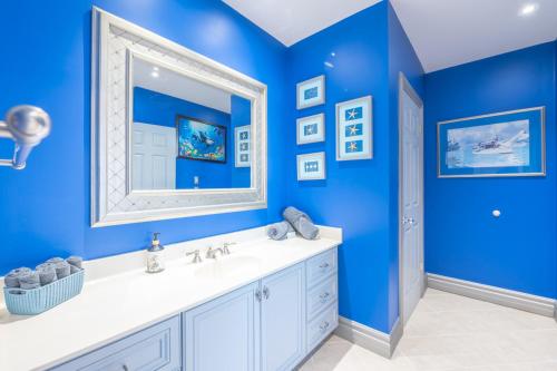 a blue bathroom with a sink and a mirror at Lux Lakeside Escape Slps 20 with Pool, Golf Sim, Hot Tub, Karaoke, Gym and Sauna in Peterborough