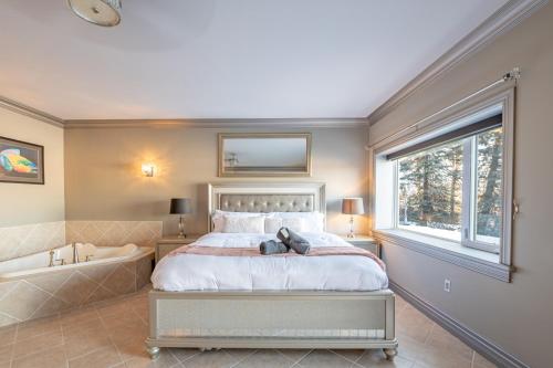 a bedroom with a large bed and a bath tub at Lux Lakeside Escape Slps 20 with Pool, Golf Sim, Hot Tub, Karaoke, Gym and Sauna in Peterborough