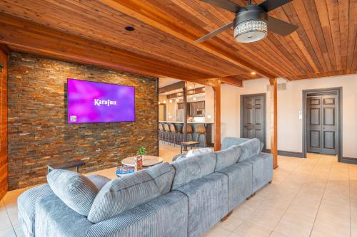 a living room with a couch and a tv on a brick wall at Lux Lakeside Escape Slps 20 with Pool, Golf Sim, Hot Tub, Karaoke, Gym and Sauna in Peterborough