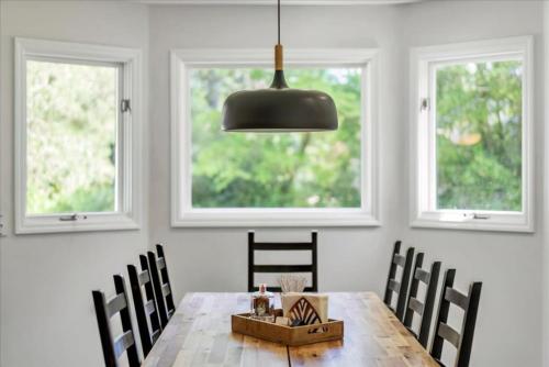 a dining room with a wooden table and two windows at Spacious property with Pool and walkable to downtown in Pinehurst