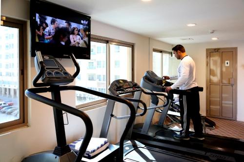 a man in a gym with a tv and a treadmill at Monroe Hotel & Suites in Manama