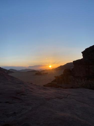 a sunset in the desert with the sun setting at Wadirum Zeid camp&Tours in Wadi Rum