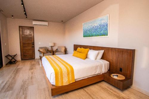 a bedroom with a large bed with yellow pillows at Hotel Flores de Sal-Valle de Guadalupe in Valle de Guadalupe