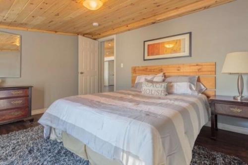 een slaapkamer met een groot bed en een houten plafond bij Westlake Consecon Cottage in Wellington
