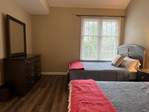 a bedroom with two beds and a dresser and a mirror at Golf Front Longleaf Condo2BR 2BA in Southern Pines