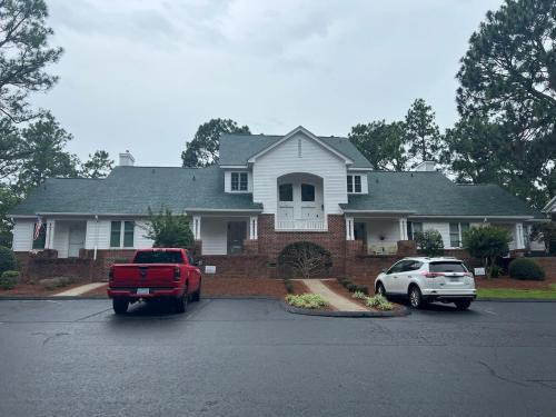a red truck and a white car parked in front of a house at Golf Front Longleaf Condo2BR 2BA in Southern Pines