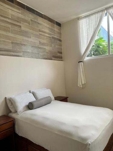 a bedroom with a white bed with a window at Hotel Awazul Bacalar in Bacalar