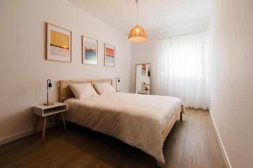 a white bedroom with a large bed and a window at Casa do Sargaço Moledo in Moledo