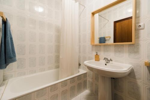 a white bathroom with a sink and a bath tub at Casa do Sargaço Moledo in Moledo