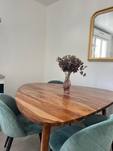 a vase of flowers on a wooden table with chairs at Appartement moderne et spacieux 4 in Carbon-Blanc