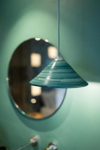 a reflection of a green lamp in a mirror at Oikos Rooms in Marsala