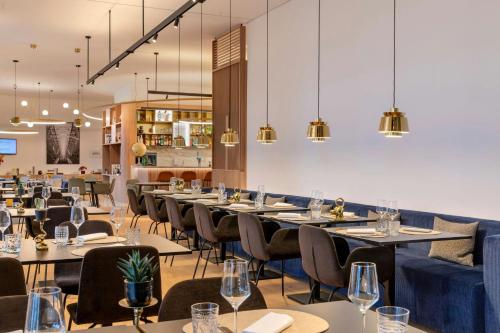 a dining room with tables and chairs and chandeliers at Courtyard by Marriott Biel Bienne in Biel