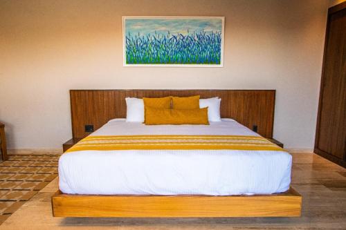 a bedroom with a large bed with yellow pillows at Hotel Flores de Sal-Valle de Guadalupe in Valle de Guadalupe