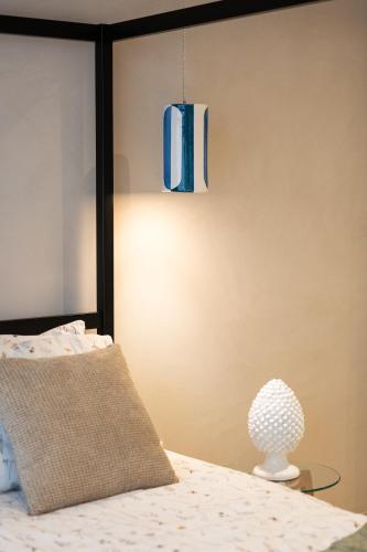 a bedroom with a bed with a blue lamp at Oikos Rooms in Marsala