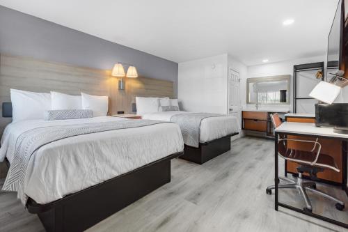 a hotel room with two beds and a desk at Inland Inn & Suites in San Bernardino