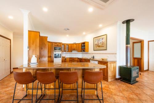 a kitchen with a large island with chairs around it at Crystal Palms - LJHooker Yamba in Yamba