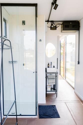 a glass shower door in a room with a sink at Container Experience in Jacareí