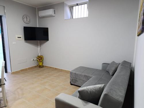 a living room with a gray couch and a flat screen tv at Le follie in Maddaloni