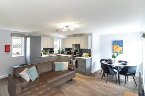 a living room and kitchen with a couch and a table at Redwood Escape Stylish New Forest Stay Sleeps 4 Near Paultons Park in Ower