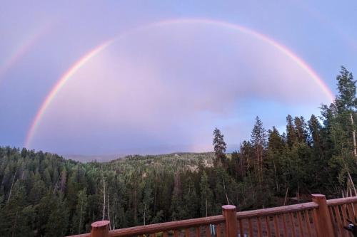 a double rainbow in the sky over a forest at New Log Home, Hot Tub For 8, Views! in Tabernash
