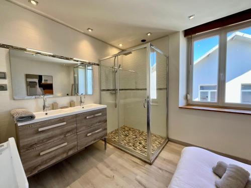 ein Badezimmer mit Dusche, Waschbecken und Spiegel in der Unterkunft Appart de Robert, nid de luxe au centre-ville in Gérardmer