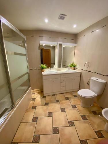 a bathroom with a toilet and two sinks and a shower at El palacio de Juana in Tordesillas
