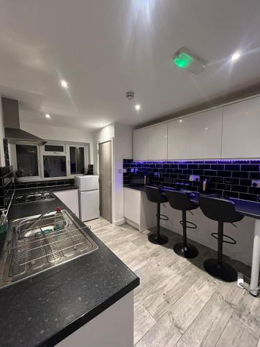 a large kitchen with blue tiles on the walls and counters at Large 6 Bed 6 Bathroom House - Ideal For Families, Large Groups, Contractors & Business Travellers in Watford