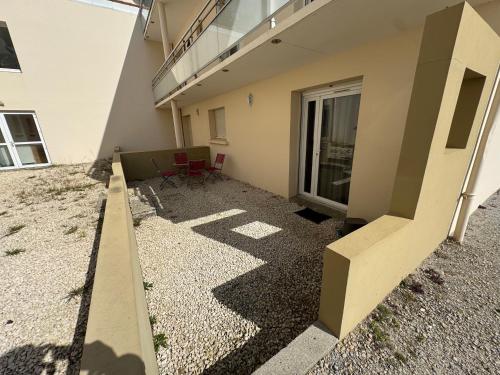 eine Terrasse eines Gebäudes mit einem Tisch und Stühlen in der Unterkunft Les Voiles Blanches, T3 neuf de 53 m2 in Saint-Jean-de-Monts