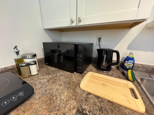 a microwave sitting on a kitchen counter with a cutting board at Lakeview Retreat in Oshawa